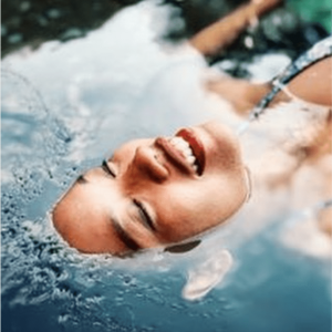 Frau taucht im Waser, nur das Gesicht schaut heraus