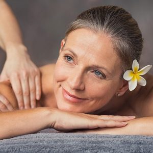 Lächelnde Frau bie der Massage mit Blume im Haar